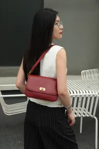 Detailed view of the red leather underarm shoulder bag worn by model, highlighting texture.