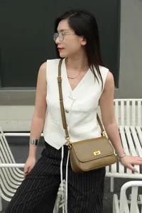 Detail view of genuine leather vintage crossbody bag with metal turn-lock and adjustable strap.