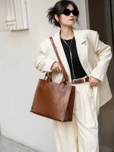 Dettaglio della borsa tote retrò in pelle marrone con texture cerata liscia e design.