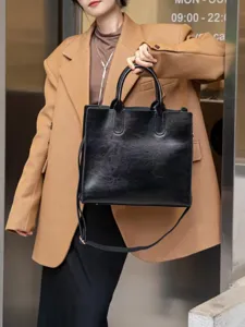 Vista dettagliata di borsa tote in pelle nera con manici e tracolla, stile quotidiano.