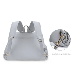 Grauer gesteppter Wickelrucksack mit Metallbeschlägen und abnehmbarem Schultergurt.