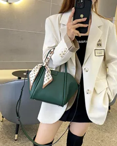 Vista detallada del bolso de cuero verde oscuro con un pañuelo y correa elegante.