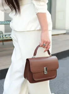 Detailed view of women's brown leather crossbody bag with metal lock, elegant daily style.