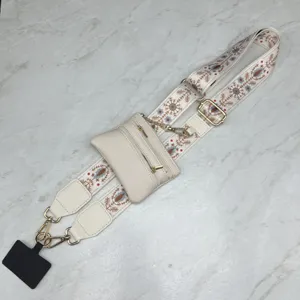 Detail view of a wide woven replacement bag strap with coin purse, adjustable beige strap and gold.