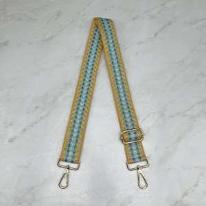 Gros plan détaillé de la large sangle de sac tissée avec motif bleu jaune et quincaillerie dorée.