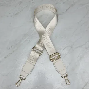 Detail view of the adjustable beige woven crossbody bag replacement strap with gold hardware.