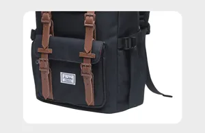Detailed view of black canvas backpack with brown leather straps and front pocket design.