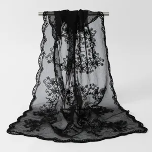 Détail d'une longue écharpe en dentelle noire brodée avec des bords festonnés élégants.