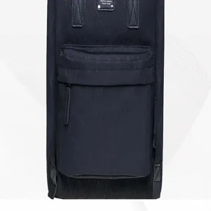 Detailed view of the black canvas backpack featuring front zip pocket and leather patch accent.