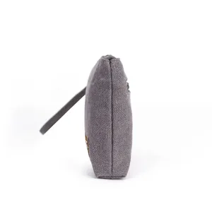 Grey canvas coin purse clutch bag side view showing minimalist design and wrist strap.