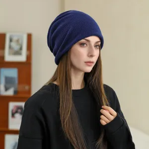 Close-up detail of a soft blue knitted slouchy beanie hat worn by a model indoors.