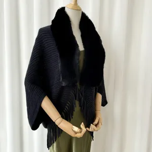 Black knitted cape detail, featuring luxurious faux fur collar and elegant fringe hem for winter wear.