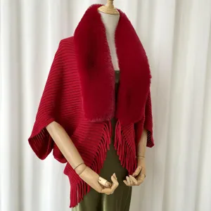 Red knit fringe cape with plush faux fur collar, stylish winter outerwear detail view.