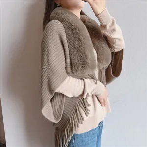 Details of stylish women's winter knitted cape with cozy faux fur collar and fringe design.