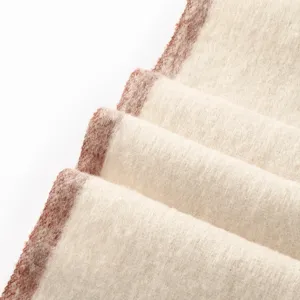 Close-up detail of thickened warm winter scarf fabric with soft wool texture and contrast edge.