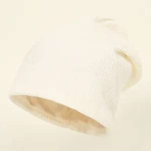 Closeup of women's warm knitted slouchy beanie hat in off-white with smooth inner satin lining detail.