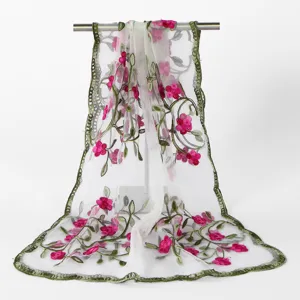 Detailed view of sheer embroidered floral scarf showing delicate pink flowers and green lace edge.