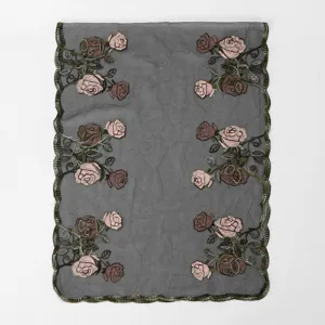 Detailed view of women's sheer embroidered scarf featuring pink roses and scalloped lace edge.