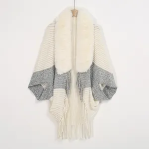 Detailed view of knitted shawl cape featuring plush faux fur collar and stylish fringe hem.