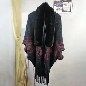 Detailed view of black knitted cape with luxurious faux fur collar and elegant fringe edges.
