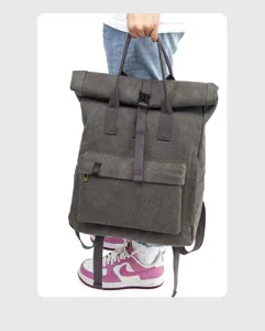 Detailed view of the dark grey canvas roll-top backpack with top handles and front pocket.