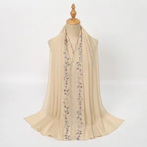 Detailed view of the elegant beige embroidered floral scarf, featuring delicate lace trim.