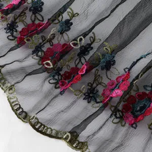 Close-up view of sheer black mesh fabric featuring colorful floral embroidery and trim.