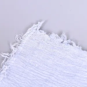 Detailed close-up of a solid color crinkled cotton linen scarf with stylish frayed edges.