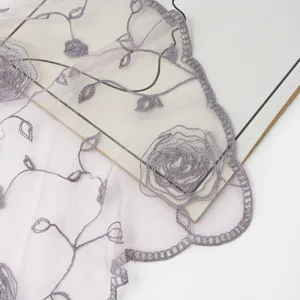 Close up detail of sheer mesh nylon fabric with elegant grey rose embroidery and lace trim.
