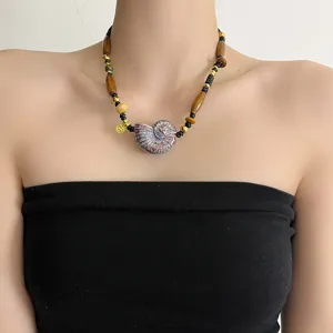 Detail shot of vintage ceramic conch shell pendant necklace with wooden beads and black rope.