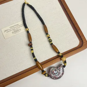 Close-up view of the handmade ceramic conch pendant necklace, featuring braided cord and wooden beads.