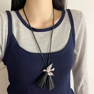 Nahaufnahme der eleganten schwarzen Lederkordelkette mit Silbervogel und Quaste im Detail.