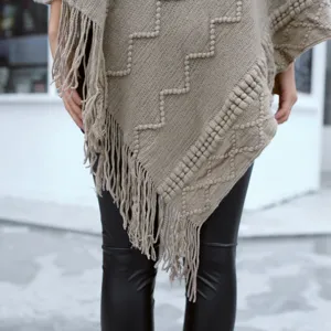 Close-up view of the knitted fringe poncho showcasing textured geometric patterns and details.