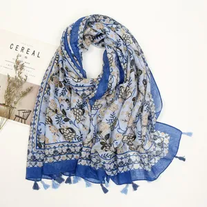 Close-up of blue floral tassel scarf with vintage botanical print and soft fabric details.