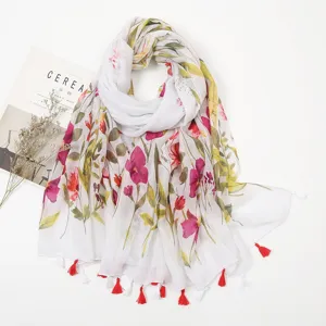 Detailed close-up view of white floral print scarf with red and white tassels, soft linen texture.