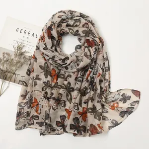 Close-up detail of the lightweight butterfly print scarf, elegant draped style for spring.