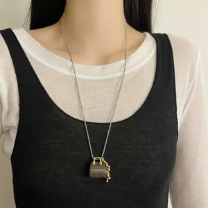 Detail view of a long tiger's eye stone handbag pendant necklace with gold beads and fine chain.