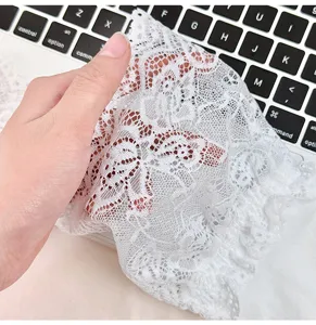 Detailed close-up of white floral lace fabric trim, showing delicate texture and fine details.