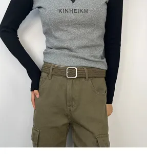 Close-up view of the khaki woven canvas belt with a silver square buckle worn on cargo pants.