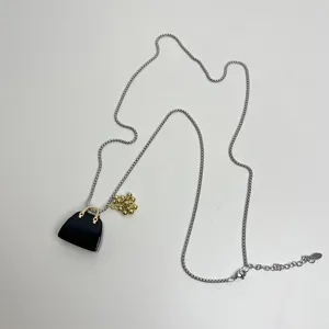 Long sweater chain featuring a black bag and gold grape pendant with a silver metal chain.