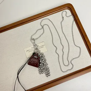 Long silver ball chain necklace featuring mini handbag pendant and elegant charm cluster.