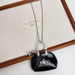 Black mini handbag pendant necklace with silver bead chain and cute grape cluster charm detail.