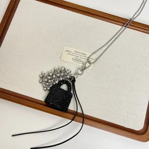 Long sweater necklace featuring a chic black beaded bag pendant and delicate silver ball chain.