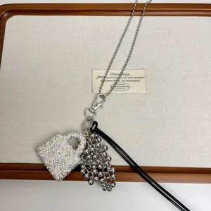 Niche design long sweater chain necklace featuring a rhinestone bag pendant and metal grape cluster.