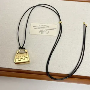 Detailed view of the gold mini handbag pendant necklace with black cord and delicate display.