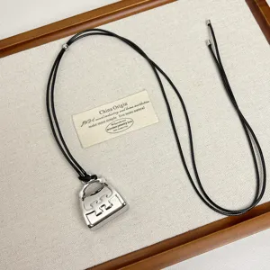 Detailed shot of a stylish silver metal handbag pendant necklace with black cord. Perfect charm.
