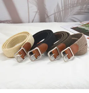 Close up detail of four woven elastic belts featuring leather ends and metal square buckles.