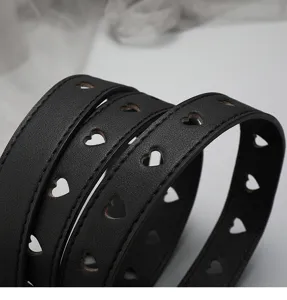 Close up detail of black leather women belt featuring stylish cutout heart shapes design.
