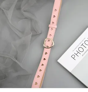 Detailed view of women's pink leather belt featuring chic heart hollow-outs and golden buckle.