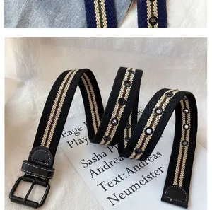 Canvas belt detail showing black striped design with metal eyelets and buckle.
